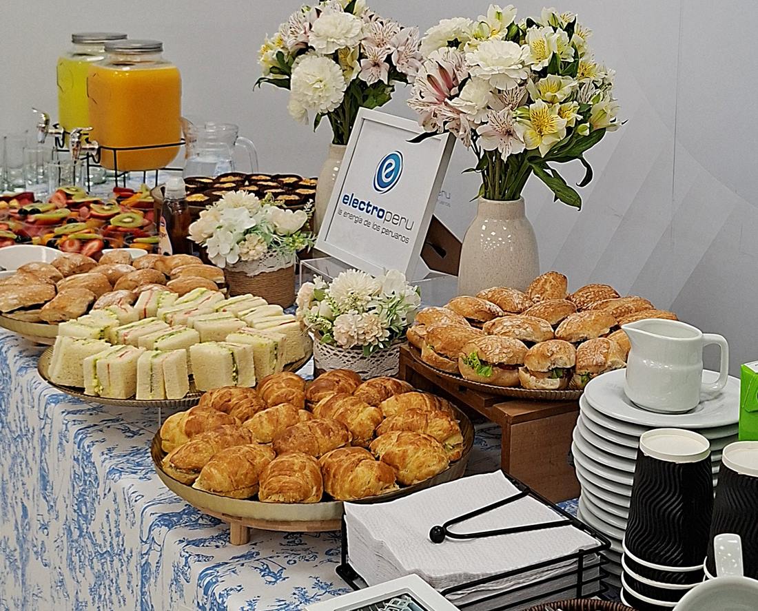 Mesa de catering corporativo con jugos, fruta, sándwiches y croissants en Lima