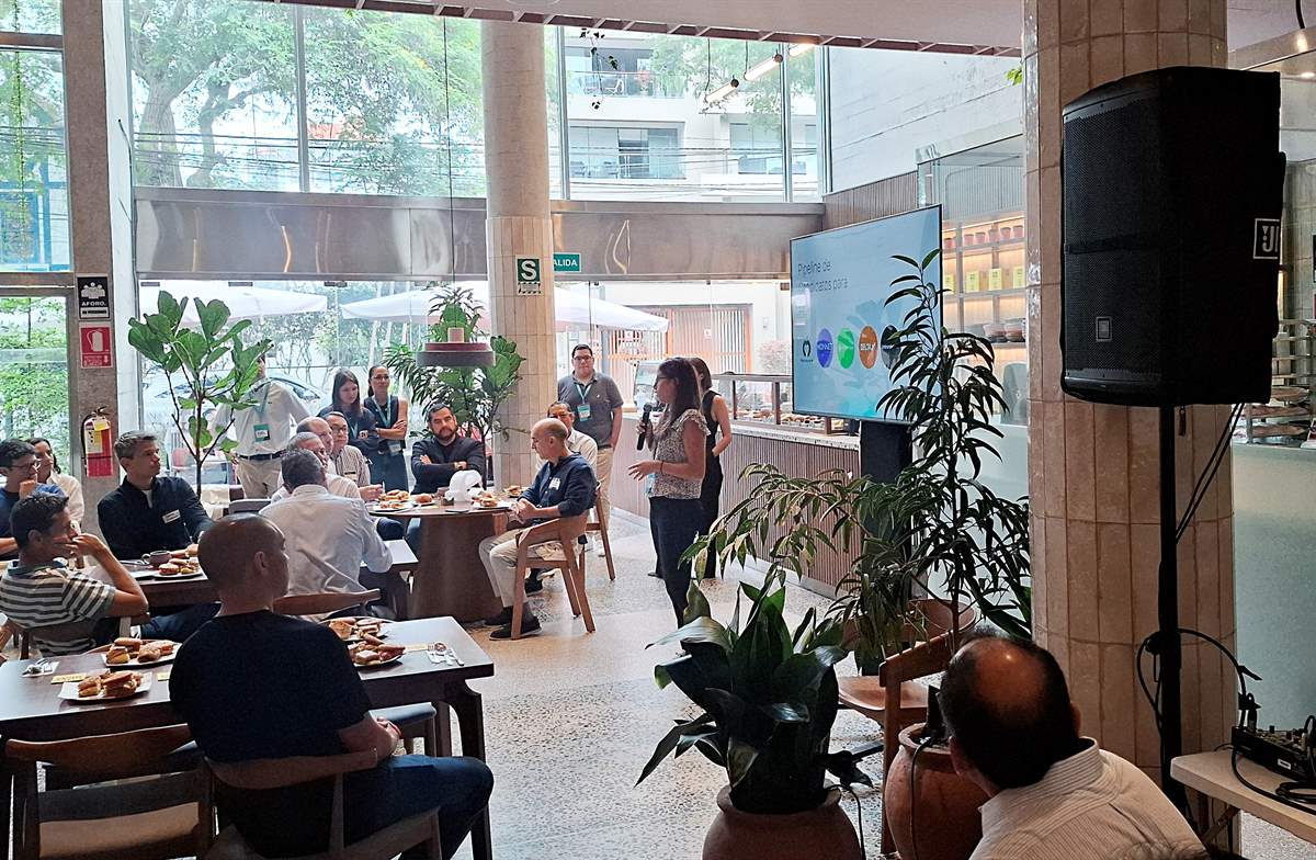 Evento corporativo atendido por Delicias Ali con bocaditos en las mesas, parlante, micrófono y pantalla